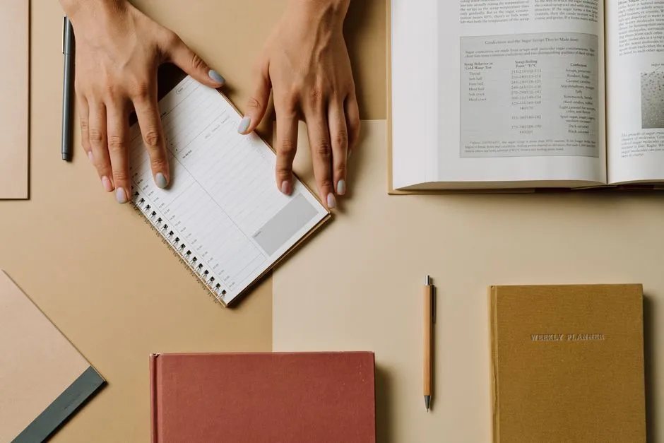 A woman writing in a weekly planner notebook at a desk